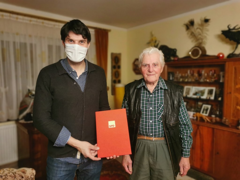 Christian Winter (links) ehrt den Jubilar mit einer Urkunde in rotem Einband für 75 Jahren Parteimitgliedschaft.