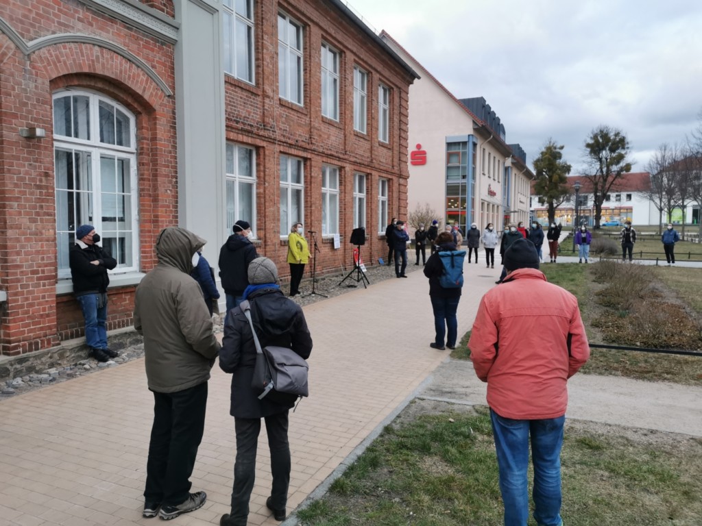 Mehrere Menschen stehe mit großen Abständen vor dem Zebef in Ludwigslust. Die Neustädter Bürgermeisterin Radelow steht am Mikrofon.