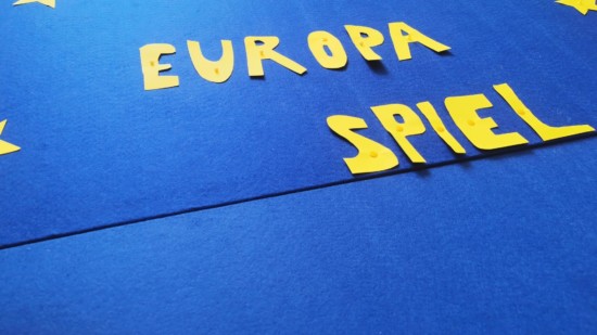 Auf blauem Untergrund steht in gelben Lettern Europaspiel, umrahmt von gelben Sternen