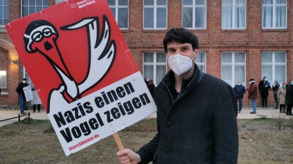 Christian Winter steht mit einem Schild "Nazis den Vogel zeigen" von Stroch Heinar vor dem Zebef in Ludwigslust.